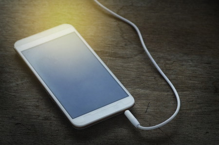 phone media portable and smart phone on dark tone. earphones and smartphone on wood table, selective...