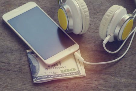 phone media portable and smart phone on dark tone. earphones and smartphone on wood table, selective focus of earphones.の写真素材