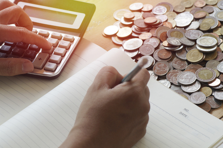 hand press calculator on wood table with coins in work placeの写真素材