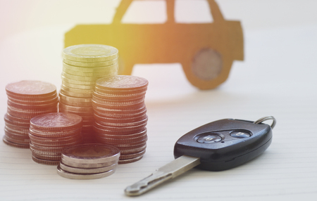 pile of money coins and key, concept in insurance,loan,finance and buying car backgroundの写真素材