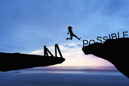 silhouette people jumping over the rock frome word impossible to possibleの写真素材