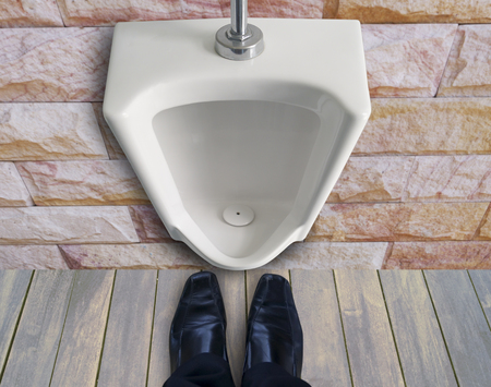 man standing infront of urinals to get pee or piss in toiletの写真素材