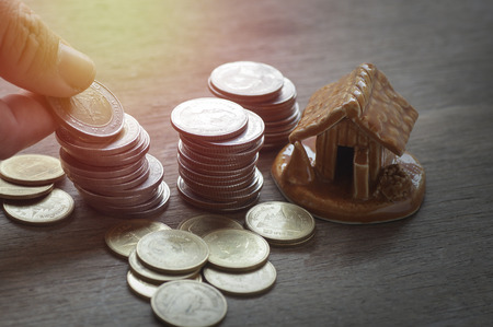 pile of coins and home, concept in house finance, account, buy and sell home on wood tableの写真素材