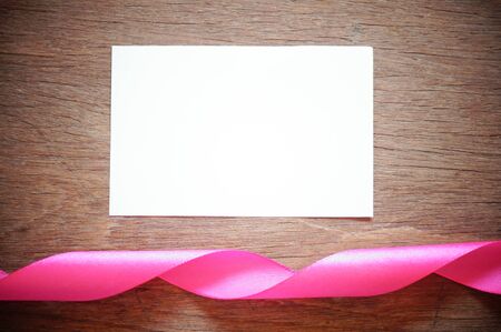 pink ribbon with white empty  paper on wood backgroundの写真素材
