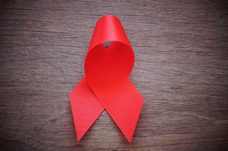 red ribbon on wood table, AIDS signの写真素材