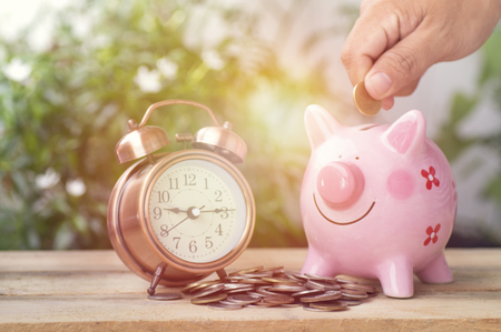hand put money on pink of piggy bank and  pile of coins, concept in growth, save and investment in businessの写真素材