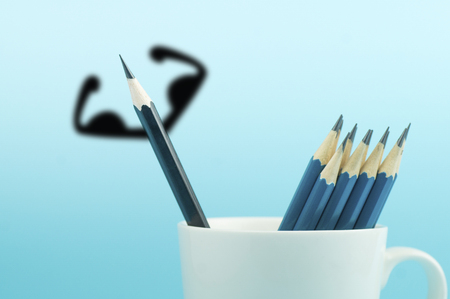 pencil with shadowed muscle in cup on blue background , concept in different and strongの写真素材