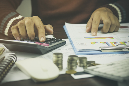 Hand of businessman writing ,pile coin money with account book finance and banking  for background.concept in grow and walk step by step for success in businessの写真素材