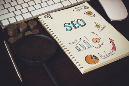 Top view of SEO and graph paper with magnifying glass, money coin on working tableの写真素材