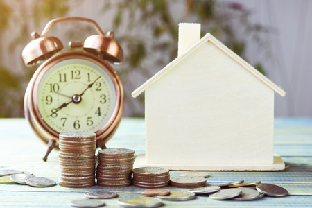 pile of money, coins  growing up with house wood and alarm clock, concept in business about loan, selling,finance, mortgage and buying homeの写真素材