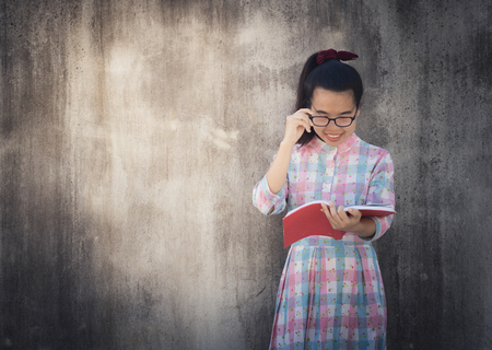 Education and knowledge concept, Beautiful young Asian woman reading book on dark cement wall background.の写真素材