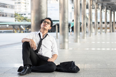 desperate and unemployed people, Economic downturn concept, frustrated man sitting on street, walkway after finding no jobの写真素材