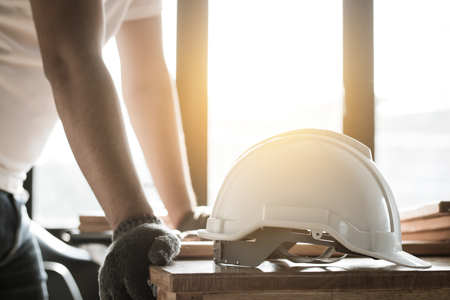 focus at safty helmet on working desk and carpenter or engineer standing and planing.の写真素材