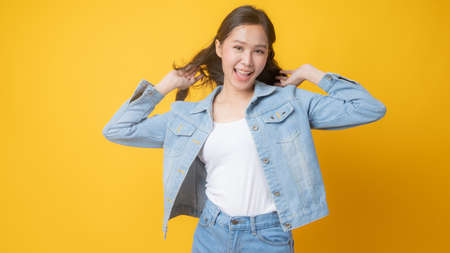 portrait woman wearing jean and shouting to announcement on yellow studio backgroundの写真素材
