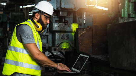 engineer working in handling hard in industrial machine, worker wearing white hard helmet control...