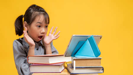 Kid sleep on table with lots of books on yellow background in studio
