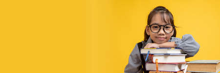 Thai Asian girl student fall down on stacked book, wearing glasses and looking camera in studio on...