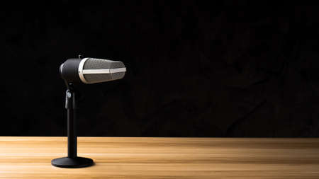 microphone for audio record or Podcast concept, single microphone on dark shadow background  on wood table with copy spaceの写真素材