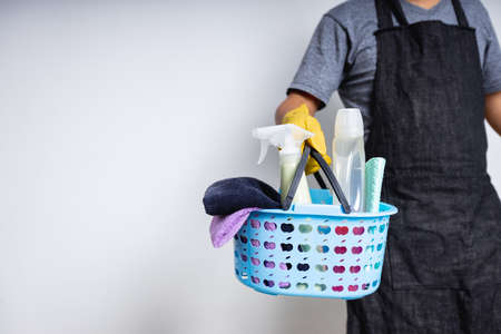 Man janitor holding basket of cleaning supplies preparing to clean at houseの写真素材