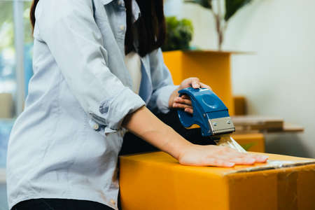 close up hand of woman packing box to move new homeの写真素材