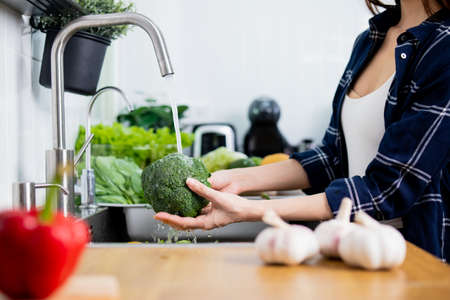 Close up Asian healthy woman washing vegetable above kitchen sink