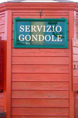 Venice Italy sign advertising Servicio Gondole (Gondola Service) on red wood backgroundの写真素材