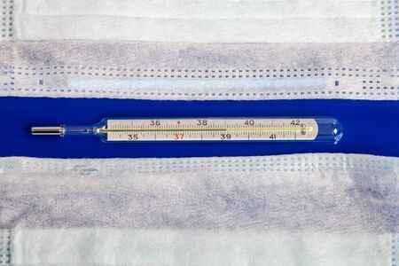 medical masks and thermometer on blue background