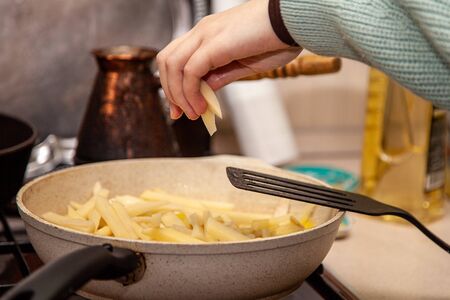 cooking fried potatoes in a pan on a home stove