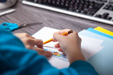 teenager's hands lined paper with pencil. making origami.のeditorial素材