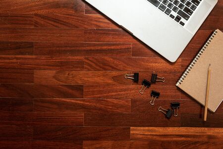 computer laptop and notebook, pencil and paperclip placed on the coner of table brown wood pattern. Top view with copy spaceの写真素材
