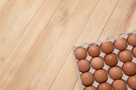 Raw chicken eggs in carton on a light brown wooden background, Top view with copy spaceの写真素材