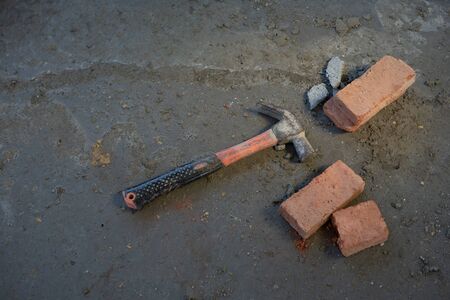 red brick and hammer put on the floor in the construction area