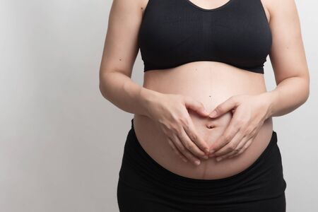 Close up of core body of pregnant woman with black bra show her hand  symbolize the heart on her...