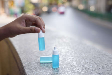 The hand picking small bottle of blue sanitizer ethyl alcohol hand gel, big and small size, place on the wall nearby the junction in the city, important thing for protect coronavirus, covid19の写真素材