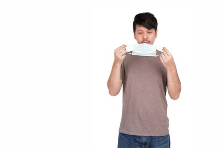 Asian man holding surgical protection face mask by two hands prepare to wear mask, look at the mask, studio light isolated on white background, concept for coronavirus, COVID19の写真素材