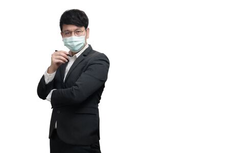 Asian businessman wearing surgical face mask in formal black suit jacket, hand holding a pen, look at the camera,  studio lighting isolated on white background, concept for coronavirus, covid19の写真素材