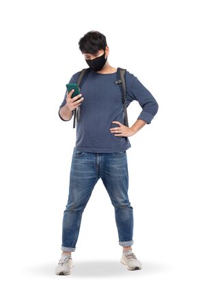 Asian man with black mask wear long-sleeved T-shirts, blue jeans, shoulder backpack, look at smartphone, isolated on white background, COVID-19 traveling conceptの写真素材