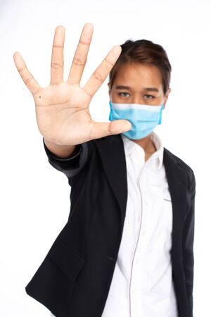 Asian businesswoman wearing face mask in formal black suit jacket, looking at camera, make hand stop with five finger, studio lighting isolated on white background, coronavirus, COVID19 conceptの写真素材