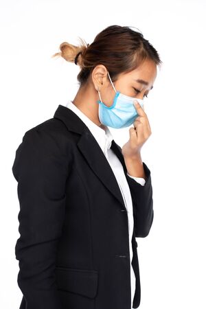 Side view of Asian businesswoman wearing surgical face mask in formal black suit jacket, touching face mask, studio lighting isolated on white background, coronavirus, COVID-19 conceptの写真素材