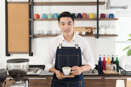 Asian barista man Pour the mixed milk into a cup of coffee. carefullyの写真素材