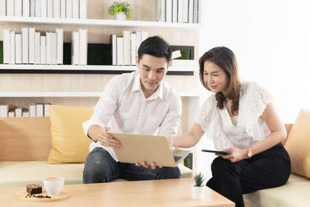 Asian man and woman use computer laptop and tablet work together in the living room of the house