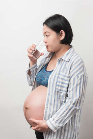 Asian pregnant woman using sanitizer hand gel to clean her hand, isolated on white backgroundの写真素材