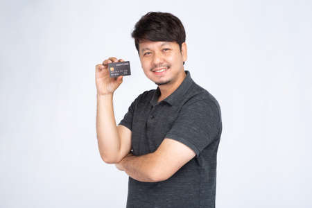 Smiling Asian man holding three credit card, look at camera, studio light portrait isolated on white...