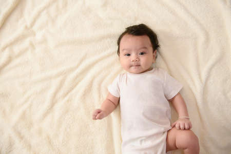 Top view of a cute Asian baby girl wrapped up in bed