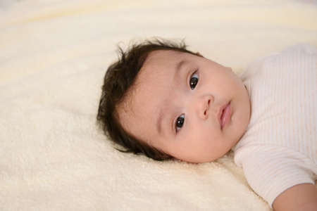 Top view of a cute Asian baby girl wrapped up in bed