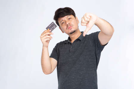 Asian man holding credit card on mouth looking at camera isolated on white background, credit card conceptの写真素材