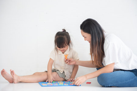 Young Asian mother taught her little daughter about reading English characters, family conceptの写真素材