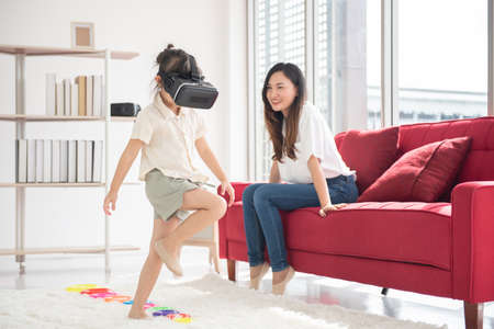 Happiness Asian young mother and little cute daughter lying on bed in the house using labtop for entertain, family joyful together in the house on holidayの写真素材