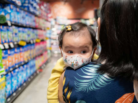 Mother holds a cute little Asian daughter wearing a mask to protect against disease.