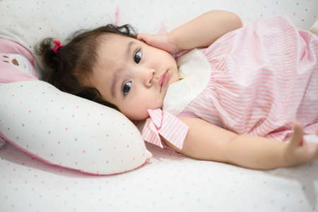 Cute little Asian baby girl lying on the bed and looking at the cameraの写真素材